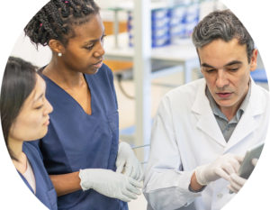 three people looking at clipboard with scrubs and latex gloves on